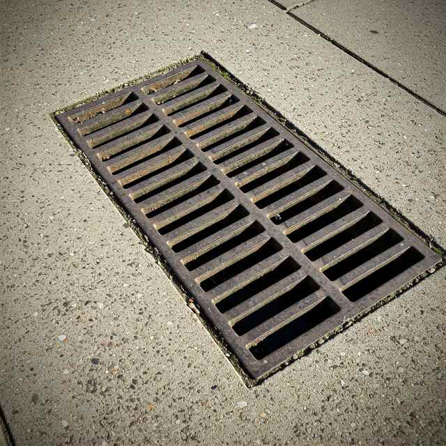 Image of a blocked drain in Gildersome with a metal drainage grate, highlighting potential drainage issues.